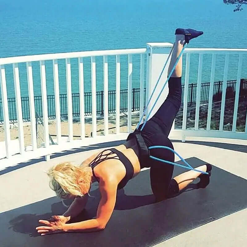 Fitness resistance bands workout outdoors for full-body toning and rehabilitation by a fit woman near the water.
